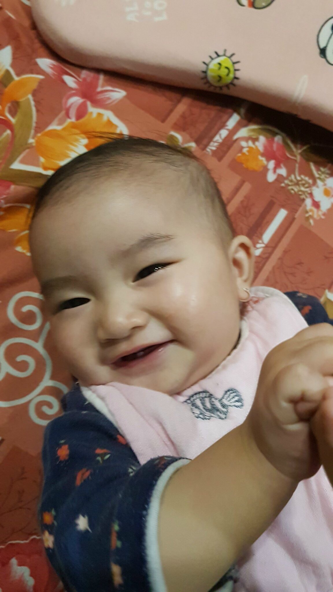 Bé gái cười tươi ngồi trong căn phòng màu hồng pastel dễ thương với gấu bông